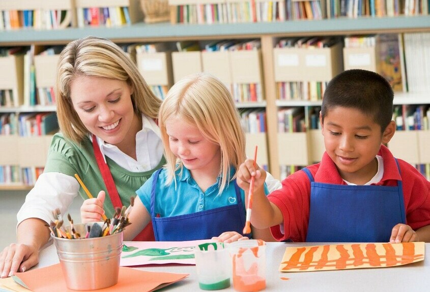 teacher with students doing art at table